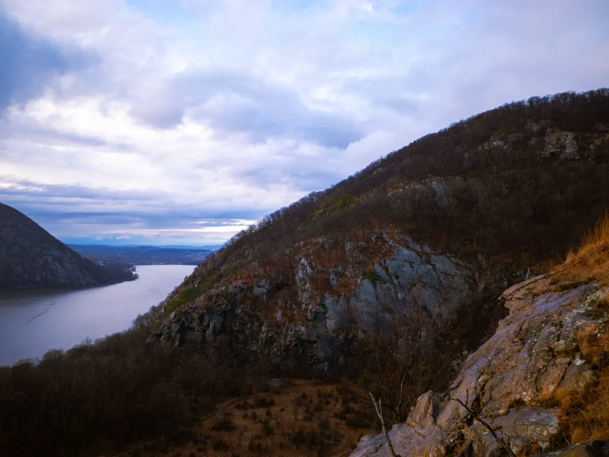Hudson River seen from a wooded hillside with low mountains on the far shore